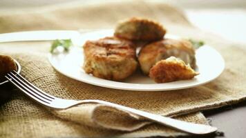 A piece of hake fish fried in a crispy crust, in a plate on a wooden table. video