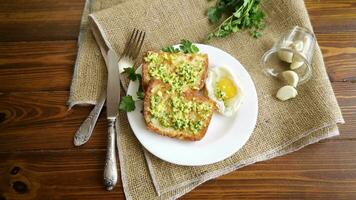 Fried croutons in batter with garlic and herbs and a fried egg in a plate, on a wooden table. video