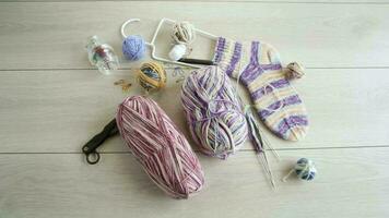 Colored threads, knitting needles and other items for hand knitting, on a light wooden table . video