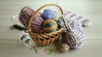 Colored threads, knitting needles and other items for hand knitting, on a light wooden table . video