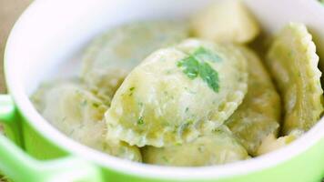 Boiled dumplings with stuffing inside, from dough with herbs in a ceramic plate. video