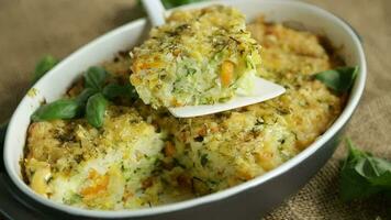 vegetable casserole of patissons, zucchini, carrots in a ceramic form on a light wooden table. video