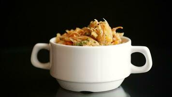 stewed cabbage with carrots and spices in a bowl on a black background. video