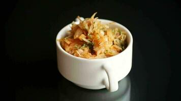 stewed cabbage with carrots and spices in a bowl on a black background. video
