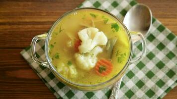 cooked chicken soup with cauliflower and vegetables in a bowl on a wooden table video