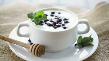 Cooked milk semolina porridge with berries and honey in a plate, on a wooden table. video