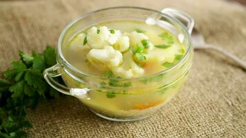 cooked chicken soup with cauliflower and vegetables in a bowl on a wooden table video