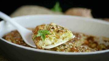 potato casserole with cabbage and spices in a ceramic form on a wooden table. video