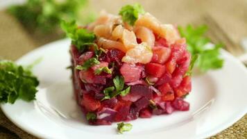 Vinaigrette Salat von gekocht Gemüse mit gesalzen Fisch im ein Platte, auf ein hölzern Tisch. video