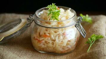 Sauerkraut with carrots and spices in a bowl on a wooden table. video