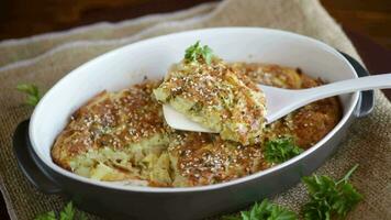 potato casserole with cabbage and spices in a ceramic form on a wooden table. video