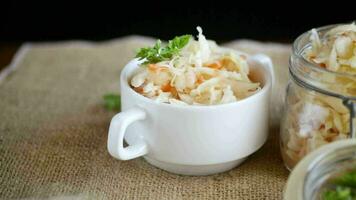 Sauerkraut with carrots and spices in a bowl on a wooden table. video