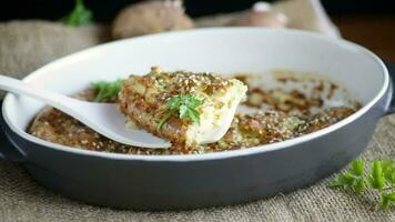 potato casserole with cabbage and spices in a ceramic form on a wooden table. video