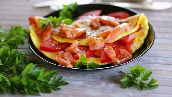 Fried omelette with tomatoes, vegetables and pieces of lightly salted red fish, on a wooden video