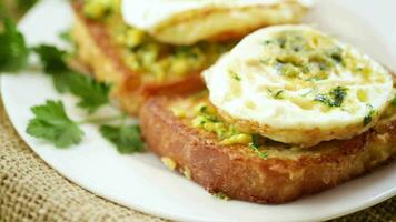 fritte crostini nel pastella con aglio e erbe aromatiche e un' fritte uovo nel un' piatto, su un' di legno tavolo. video