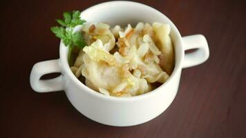 cooked dumplings with potatoes and fried onions, in a bowl on a wooden table. video