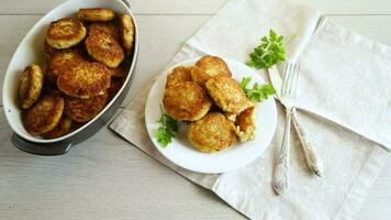 Cooked fried fish cutlets in a plate with herbs, on a light wooden table. video