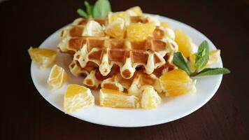 Cooked sweet Belgian waffles with oranges on a black background video