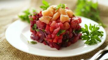 vinaigrette salad of boiled vegetables with salted fish in a plate, on a wooden table. video