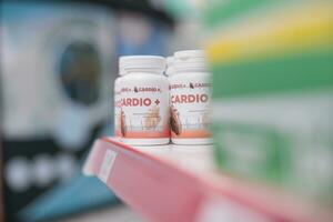 Drugstore shelves fiiled with cardiology bottle pills ready for clients to come and buy during medical visit. Pharmacy also carried a variety of other products, such as bandages and cold medicine. photo