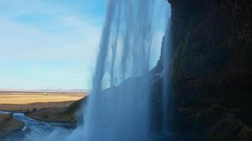 Arctic seljalandsfoss waterfall circa March 2023, water flowing down of high cliff in iceland. Natural panoramic scenery with river stream running off of mountain, icelandic cascade. Handheld shot. photo