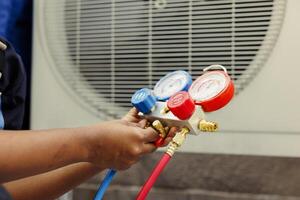 Close up of trained engineer holding manifold gauges used for checking air conditioner refrigerant. Certified technician using benchmarking barometer for high or low freon levels of hvac system photo