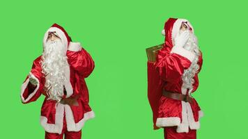 Cute santa claus sending air kisses, acting sweet with flirty gesture in greenscreen studio. Romantic man acting like saint nick on camera, carry bag with presents during christmas eve holiday. photo