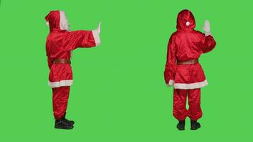 Saint nick character does stop sign, rejecting ideas with palm raised and acting disappointed over greenscreen backdrop. Person doing no gesture to refuse something, ignorance. photo