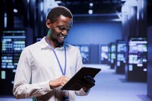 Engineer in high tech location delivering extensive computing power, capable of processing and storing vast amounts of data. Specialist walking between server rows controlling network resources photo