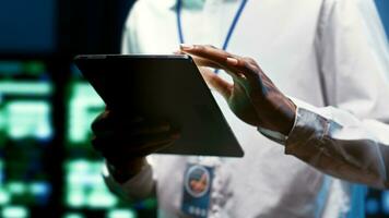 System administrator using tablet to check high tech facility security features protecting against unauthorized access, data breaches, phishing attacks and other cybersecurity threats, close up photo