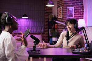 Online show host making guest laugh, cracking jokes during comedy focused podcast. Talking show interviewer broadcasting live from living room studio decorated with neon lights photo