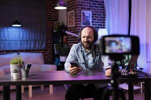 Content creator doing live broadcasting for online streaming service reading comments from audience. Internet streamer interacting with fans while recording in home studio photo