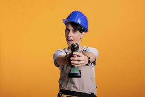 Industrial engineer acting crazy with drilling screw gun in studio photo