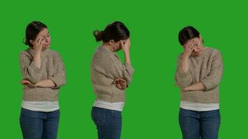 Close up of adult dealing with painful headache on camera, rubbing temples to cure sickness. Person suffering from migraine over isolated green screen backdrop, unwell ill woman in studio. photo