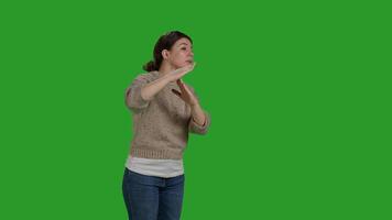 Side view of model doing t shape sign with hands, showing refusal and no sign over greenscreen backdrop. Negative bored woman expressing timeout or break gesture, rejection and disapproval. photo