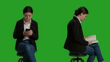 Close up of manager reading book and texting messages on camera, sitting on chair. Employee focusing on novel chapter to read tale, enjoying story and wearing suit over greenscreen backdrop. photo