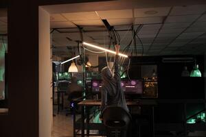 Online criminal celebrating computer system victory, successful hacking at night. Satisfied thief committing cyberattack, stealing government data and breaking into database online server. photo