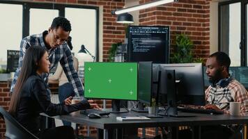 Two software developers analyzing source code looking at green screen chroma key mockup with coworker sitting at desk writing algorithm. Software developers working on artificial intelligence project. photo