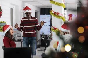 Diverse business team enjoying coffee break at work, having fun together in festive adorn office during holiday season. Colleagues feeling Christmas spirit mood, relaxing in xmas ornate workspace photo