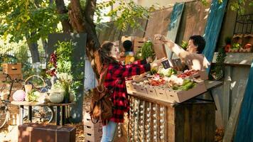 Local business owner selling healthy fruits and veggies outside at farmers market counter, presenting bio food. Young vendor giving organic eco fresh products to vegetarian client. photo