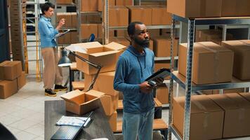 Small business owner scanning bar code on carton boxes, working on doing merchandise inventory in warehouse space. Male worker taking packages from sorage room racks and checking them. photo