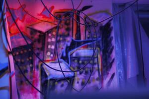 Damaged old place with fluorescent neon lights and dust on walls with graffiti art, warehouse with crumbling structure covered in messy artwork. Old abandoned space with bright lights. photo