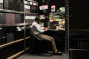 Blurred investigator solving crime, sitting at workplace table in office. Policeman working overtime at desk, conducting investigation and analyzing evidence at night time photo