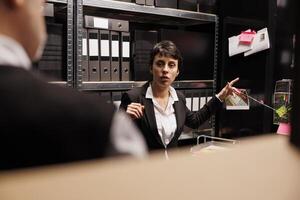 mujer investigador explicando delincuente investigación reporte a policía oficial, trabajando tarde a noche a misterioso desaparecido persona caso. caucásico privado detective analizando criminología evidencia archivos foto