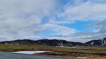 Lonely road through icelandic scenery with empty highway, frosty highlands and ice covered meadows in Iceland. Spectacular nordic landscape of with snowy mountain tops, long road concept. photo