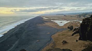 Drone shot of nordic black sand beach in iceland, majestic ocean coastline and beachfront in wintry weather, creating magical icelandic setting. Majestic atlantic shore with huge waves crashing. photo