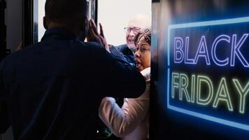 Customers shoving each other out of way to enter store first during black friday shopping spree. African american security agent holding back crazy shoppers breaking inside shopping center. photo