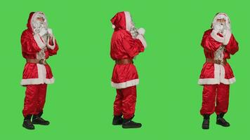 Saint nick hail someone on camera, asking people to come over and join him. Father christmas embodiment in costume calling person to accompany, full body greenscreen background. photo