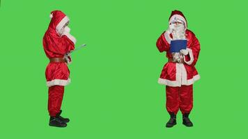 Saint nick writing data on clipboard, creating naughty or nice list of children before sending gifts for christmas eve celebration. December main character take notes on files, greenscreen. photo