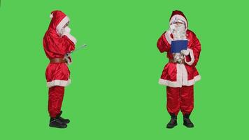 Saint nick writing data on clipboard, creating naughty or nice list of children before sending gifts for christmas eve celebration. December main character take notes on files, greenscreen. photo